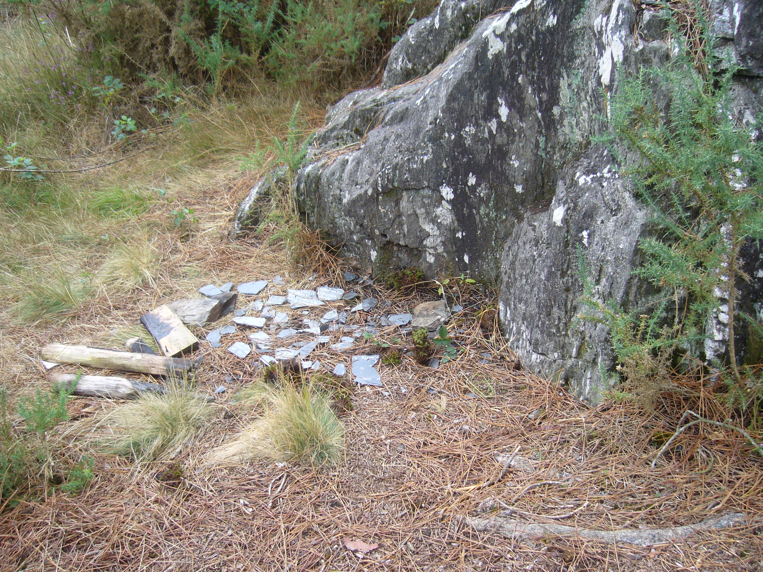 Un panneau brisé au pied d'un rocher