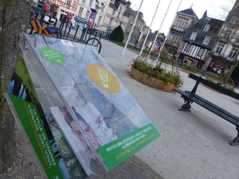 Place Maurice-Marchais à Vannes, une petite boîte à livres en plastique contenant des revues et "Pensées en chemin" d'Axel Kahn.