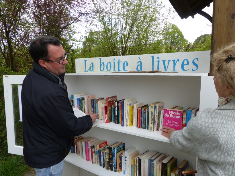 Joëlle de la médiathèque et un promeneur qui regarde ce que contient la boîte à livres